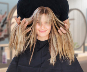 Beim KLIER Friseur im Seidnitz-Center lächelt eine Kundin mit langen Haaren freundlich in die Kamera.