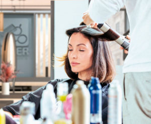 Eine Kundin wird bei KLIER mit einem Lockenstab frisiert.