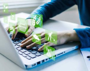 Über einem Laptop schweben grüne Symbole, die mit Smart Farming zu tun haben, während die Hände einer nicht erkennbaren Person auf der Tastatur des Laptops liegen.