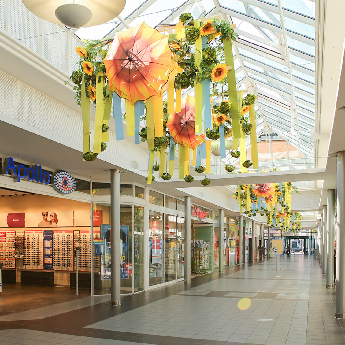 In einem Gang des Seidnitz Centers hängt Dekoration mit bunten Bändern, Regenschirmen, Sonnenblumen und Blättern von der Decke.
